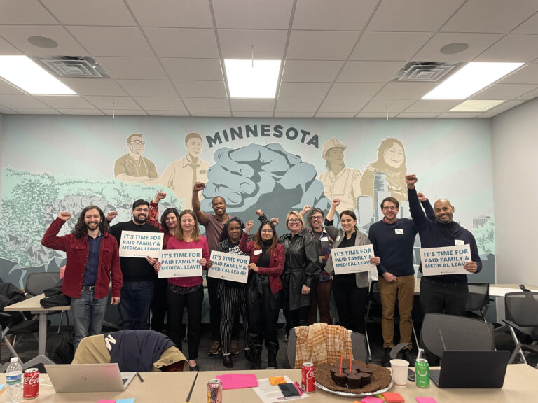 Minnesota local electeds and partners show support for statewide Paid Family and Medical Leave with signs in front of a mural.