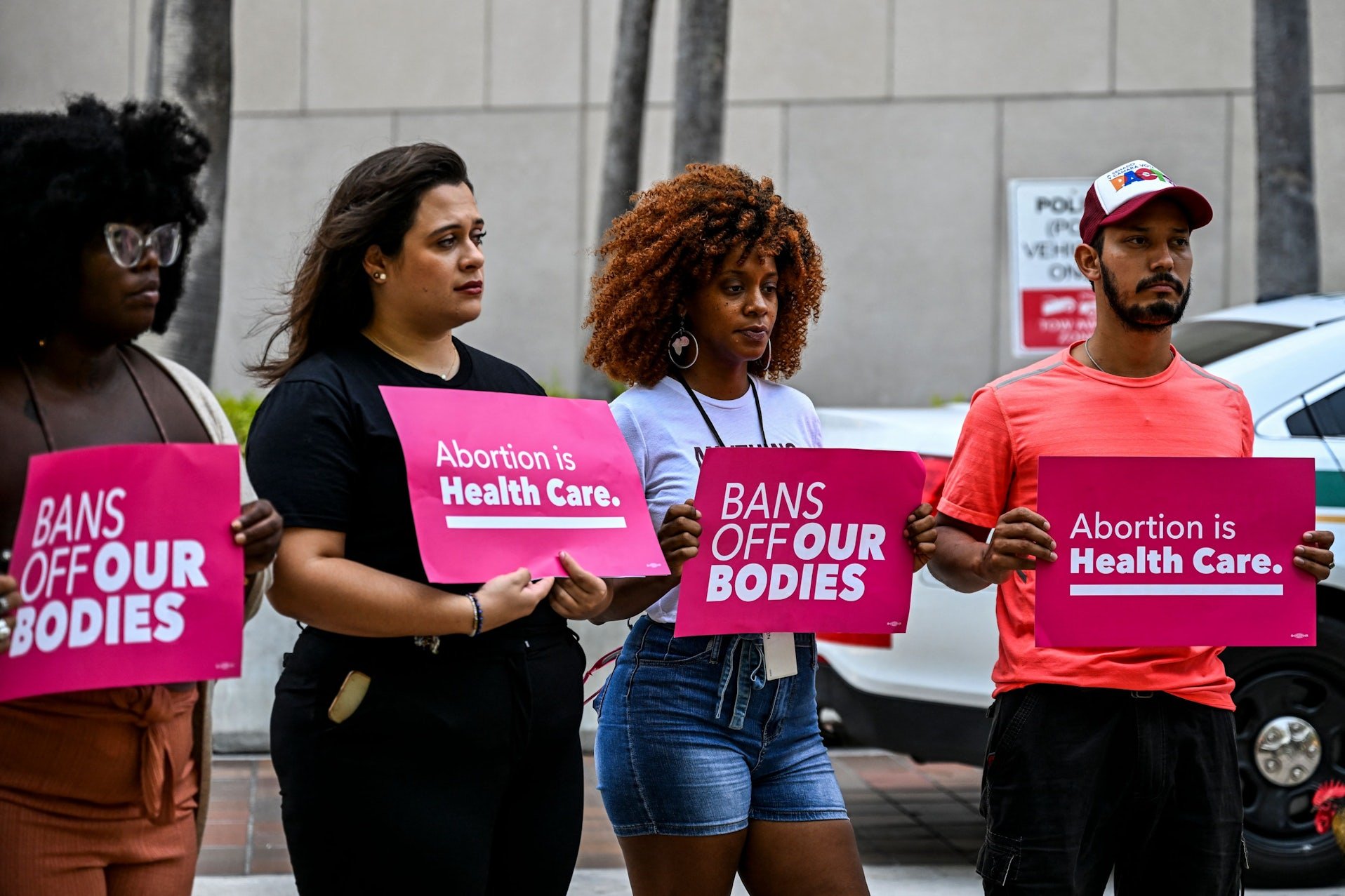 Peaceful demonstrators holding up signs saying "Abortion is health care" adn "bans off our bodies."