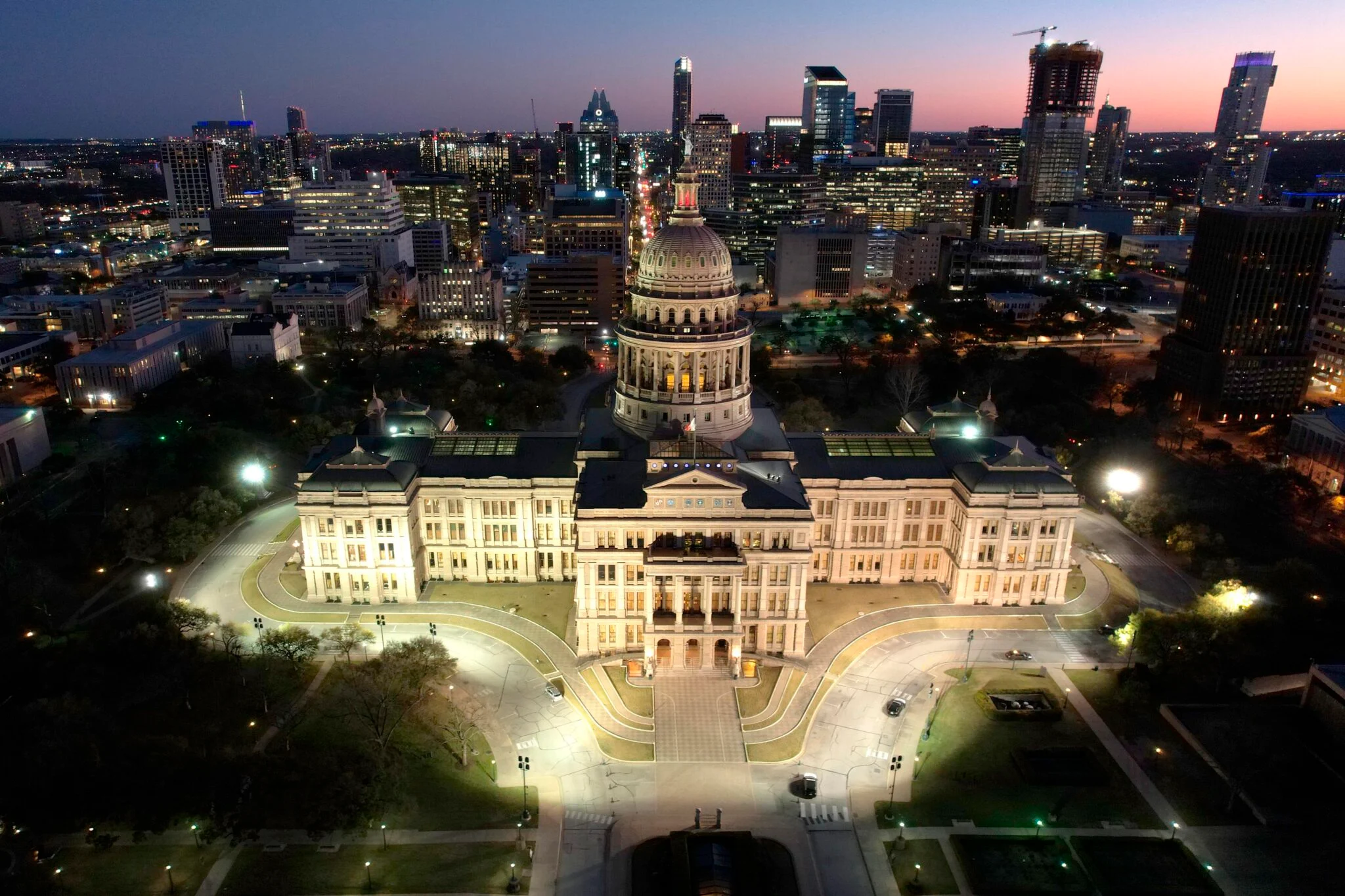 Arial view of the Texas State Capitol lit up at night.