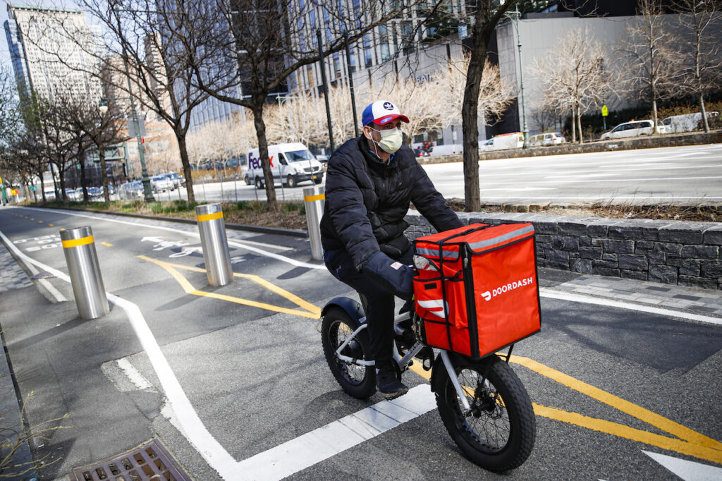 A delivery worker rides his bicycle along a path on the West Side Highway in New York City.