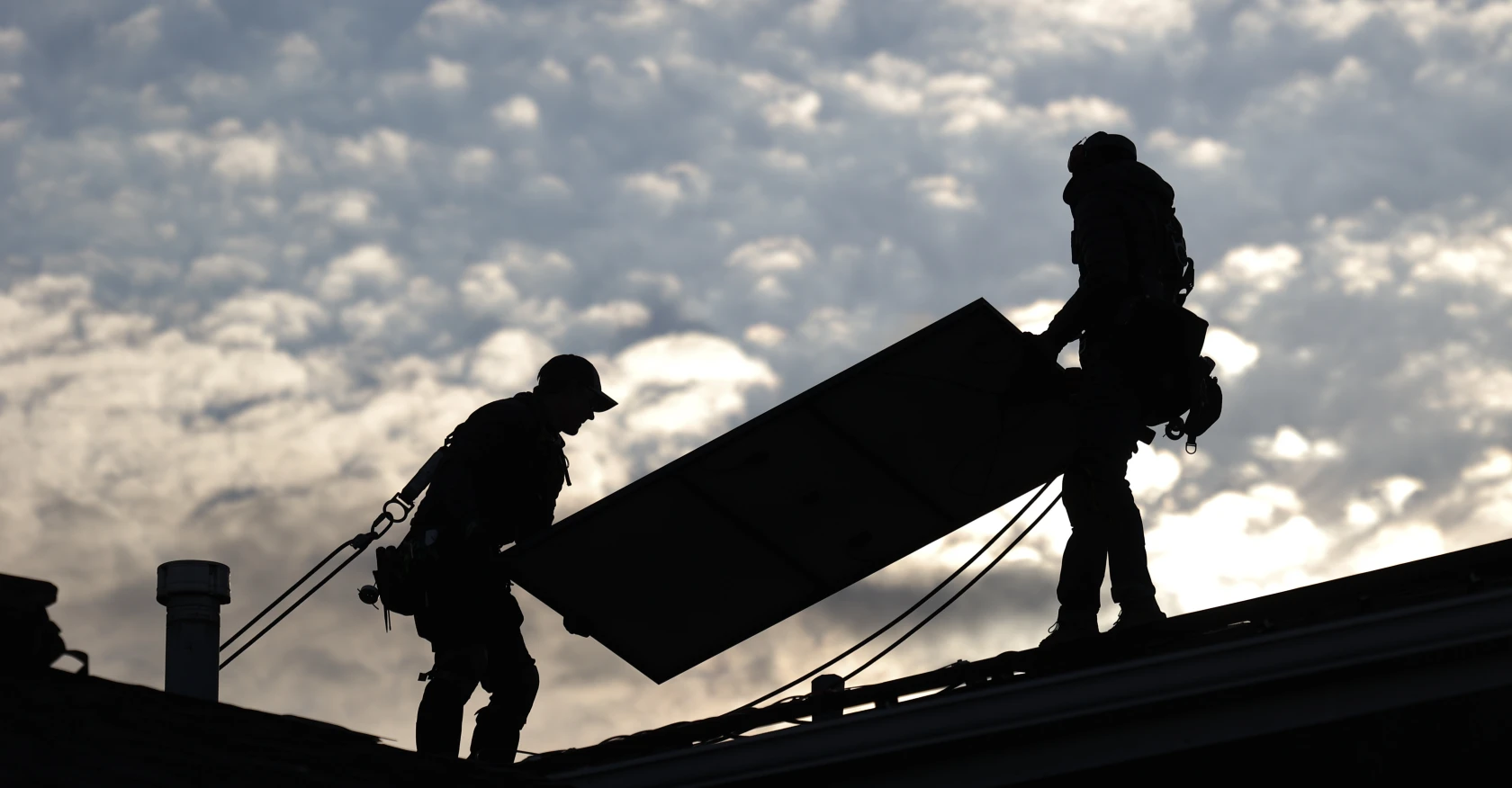 Jared Salvatore, left, and Garrison Riegel, of Celestar Solar, carry a solar panel onto a roof in Schaumburg, Ill., on Nov. 30, 2023.(Trent Sprague/Chicago Tribune)