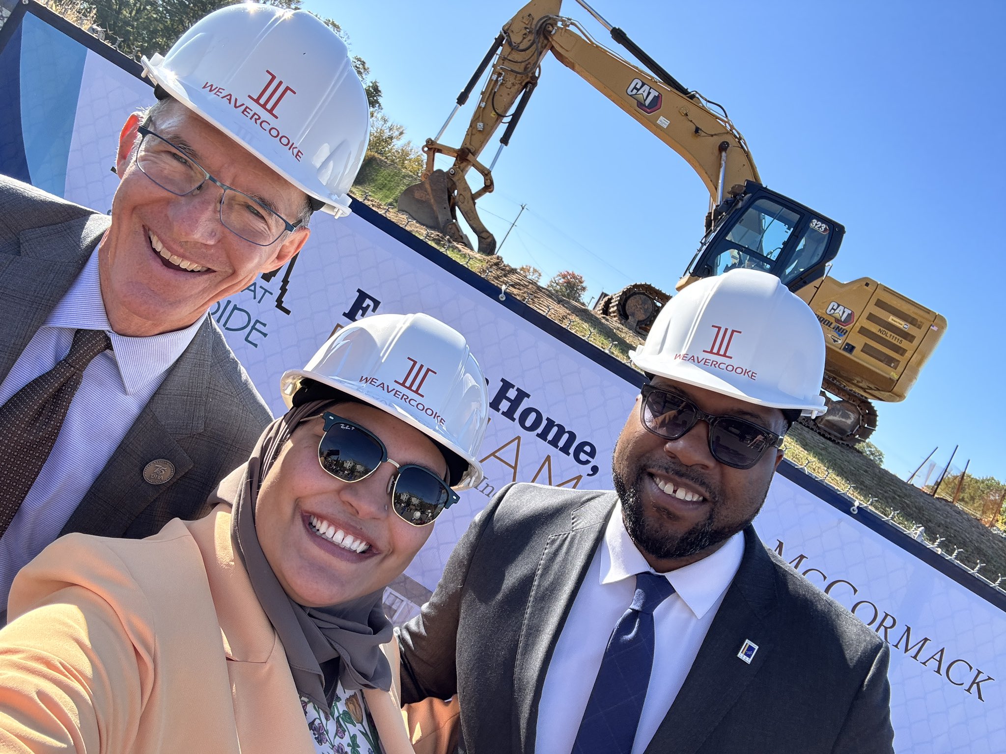 A seflie featuring LPNC Organizing Committee Member, and Chair of the Durham Board of County Commissioners Nida Allam posing with two other people in front of a construction site for new housing.