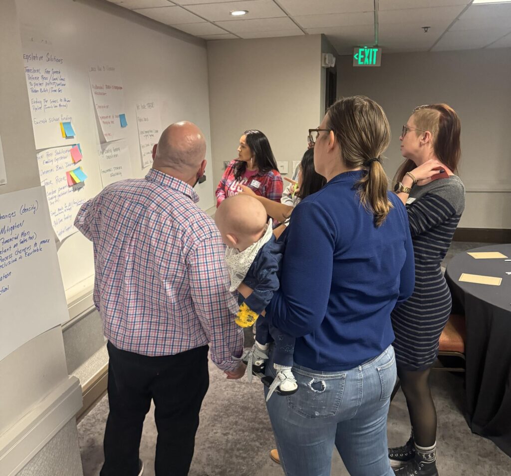 Several people looking at a wall with sticky notes on it.