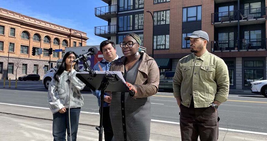 Minneapolis City Council Members Robin Wonsley, at lectern, Jason Chavez, left, and Jeremiah Ellison, right, stand in front of Cortland Mill District Apartments along with University of Minnesota undergraduate student government director of local affairs Siya Shelar to discuss the recently passed ordinance banning the use of algorithmic rent-setting software. Cortland Mill District is owned by Cortland, which is being sued by the Department of Justice for its use of rent-setting software. (Staff photo: Dan Netter)