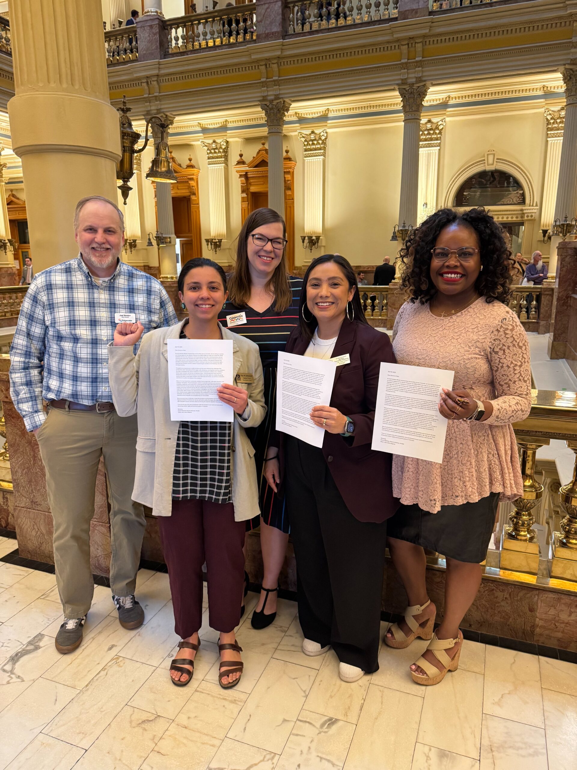 A group of local elected officials holding a letter in the Colorado state capitol