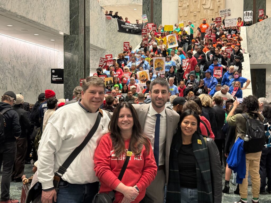 A group of people posing for a picture in front of a group protesting