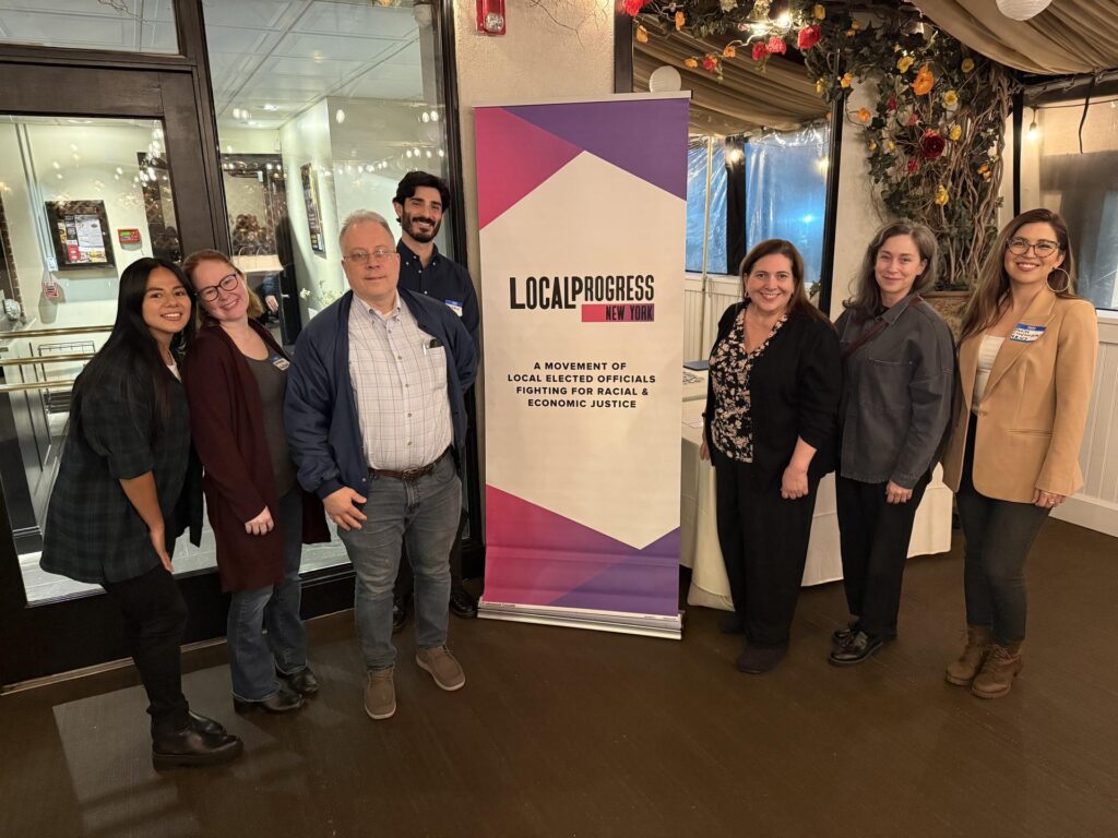 A small group of people posing in front of a sign