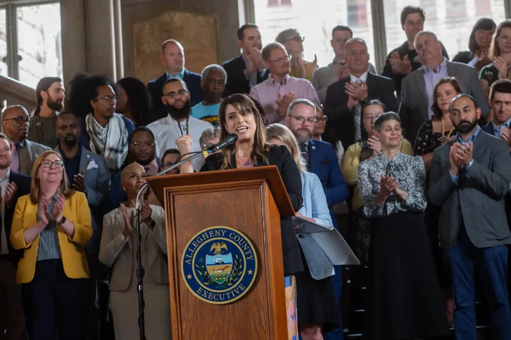 A woman speaking at a podium in front of a large group of people