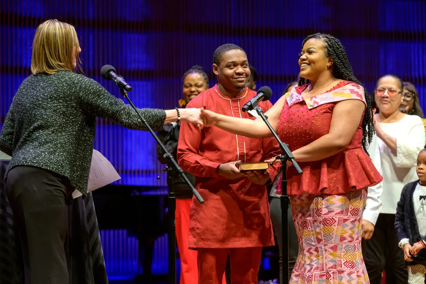 Cheniqua Johnson shaking hands with someone on stage and smiling.