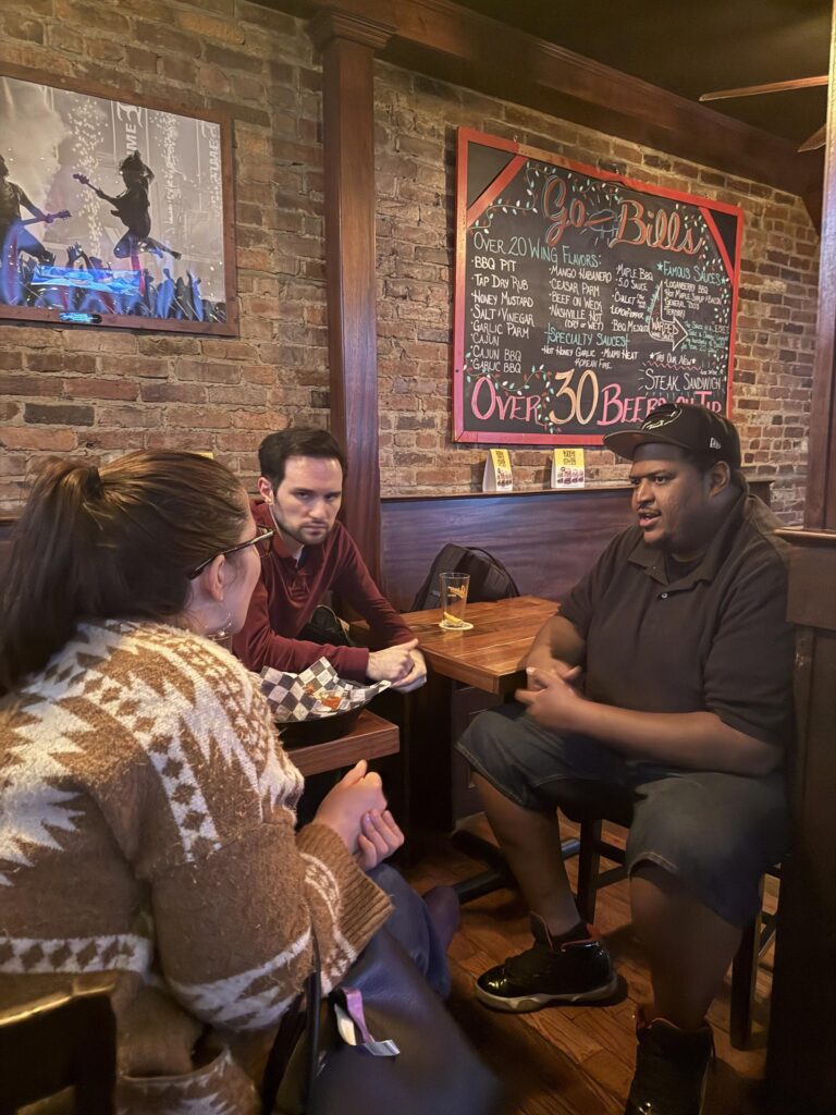 Three people sitting and chatting at a bar