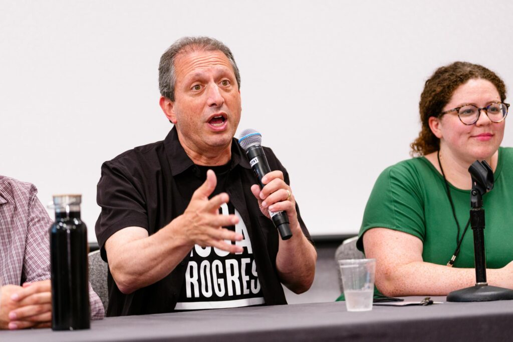 Someone speaking with a microphone on a panel