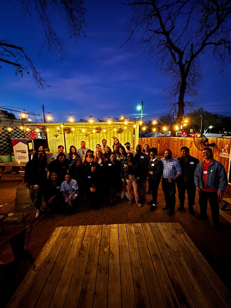 A large group of people posing of a picture in a dimly lit outside room