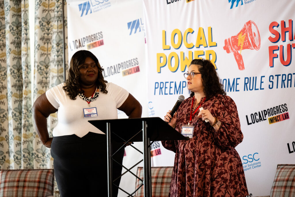 Two people standing in front of a sign with a microphone.