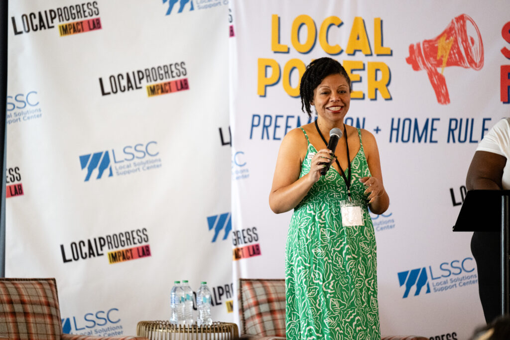 Someone standing in front of a sign with a microphone.
