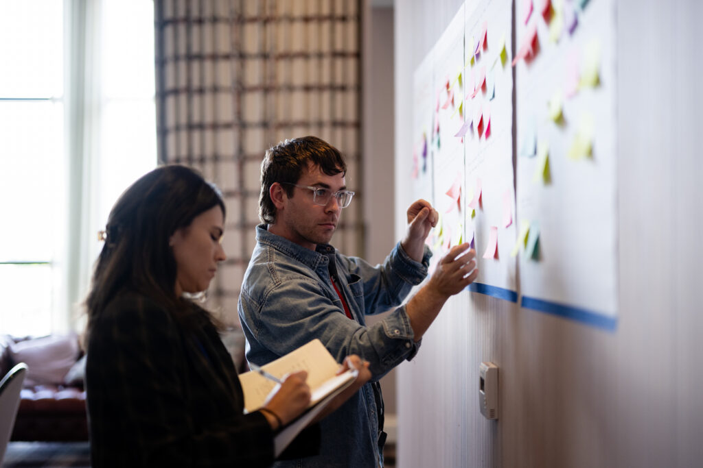People putting sticky notes on a wall
