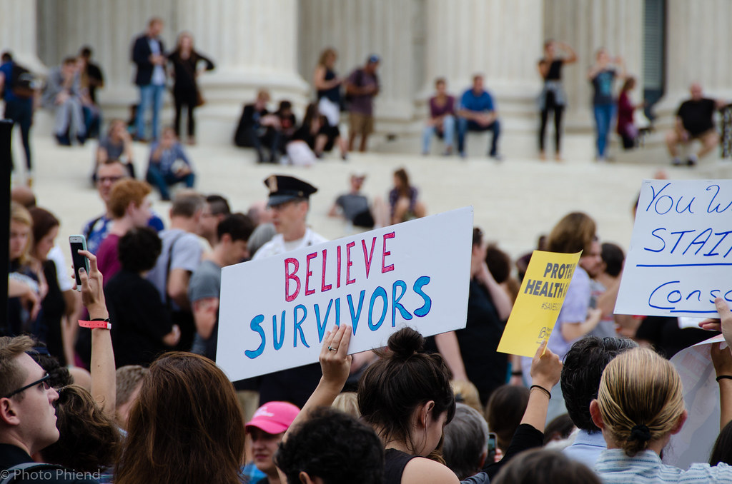 An image with a protest sign that says: Believe Survivors